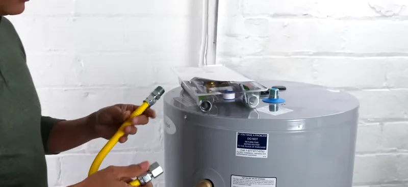 Plumber connecting a gas flex line to a water heater in a brick-walled Everett basement